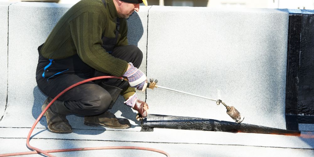 A man installing waterproofing on a roof.
