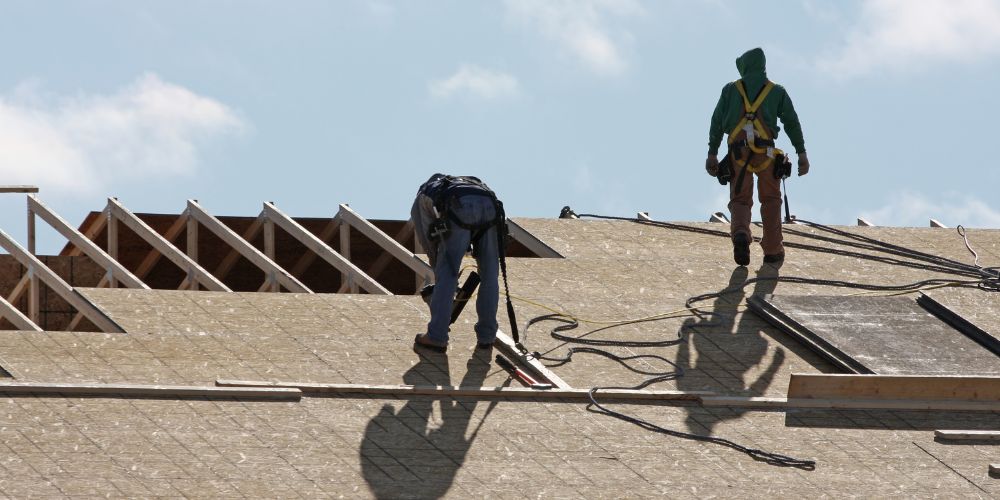Two men preparing a roof for installation of a new roof.