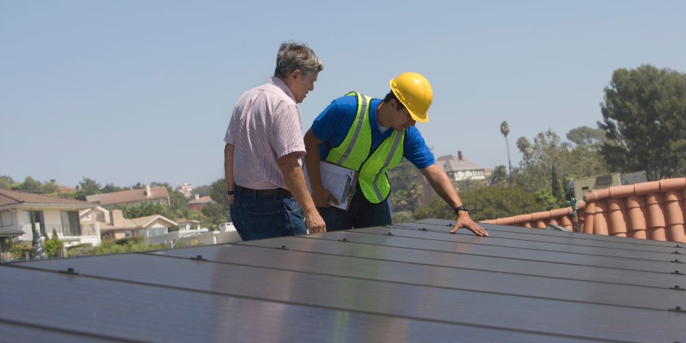 Man checking solar panel with coworker